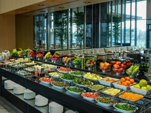 Ein reichhaltiges Buffet mit verschiedenen Speisen und Getränken, präsentiert auf einer Theke mit Tellern und Schüsseln.