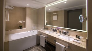 A modern bathroom with a large bathtub, two sinks, a vanity, and a large mirror. - Mövenpick Diyarbakir (Diyarbakir)