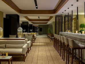 A modern hotel lobby with a bar area, sofas, and a dining setup. - Mövenpick Diyarbakir (Diyarbakir)