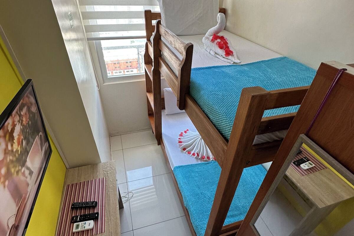 Una habitación pequeña con literas, un ventanal y un ventilador de techo.