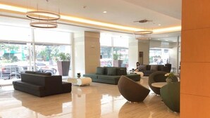 A modern lobby with a polished floor, contemporary furniture, and large windows offering a view of the street. - Green Residences (Manila)