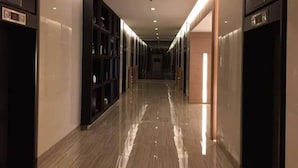 A long, narrow hallway with a polished floor, flanked by dark-colored shelving units on both sides. - Green Residences (Manila)
