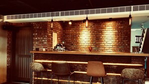 A bar area with a brick wall, wooden counter, and three bar stools. - The Upstairs (Hualien City)