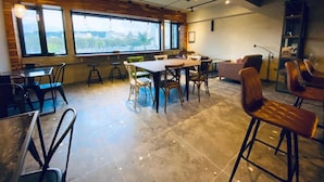 A spacious room with a large table and chairs, large windows with a view, and a modern ceiling design. - The Upstairs (Hualien City)