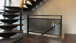 A modern staircase with a glass barrier and metal railings, leading to an upper floor. - The Upstairs (Hualien City)