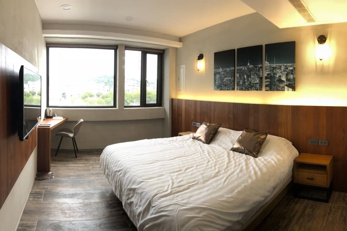 Un dormitorio moderno con una cama grande, un escritorio y un cuadro con un paisaje urbano.