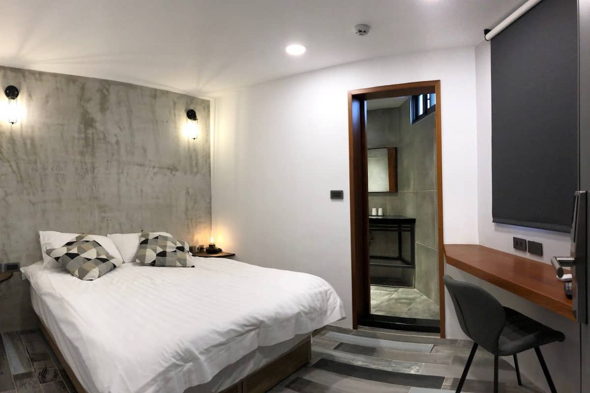Un dormitorio moderno con cama, lámparas de noche, un escritorio y un espejo.