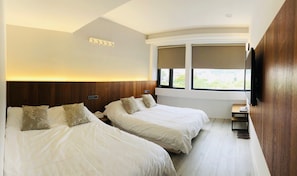 A hotel room with two beds, a small desk, a TV, and a window with a view. - The Upstairs (Hualien City)