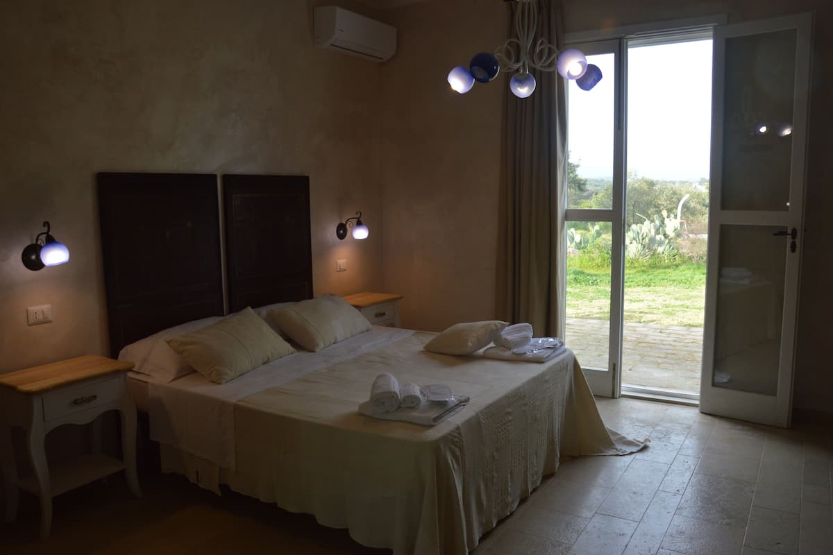 A bedroom with a bed, bedside tables, and a view through a glass door.