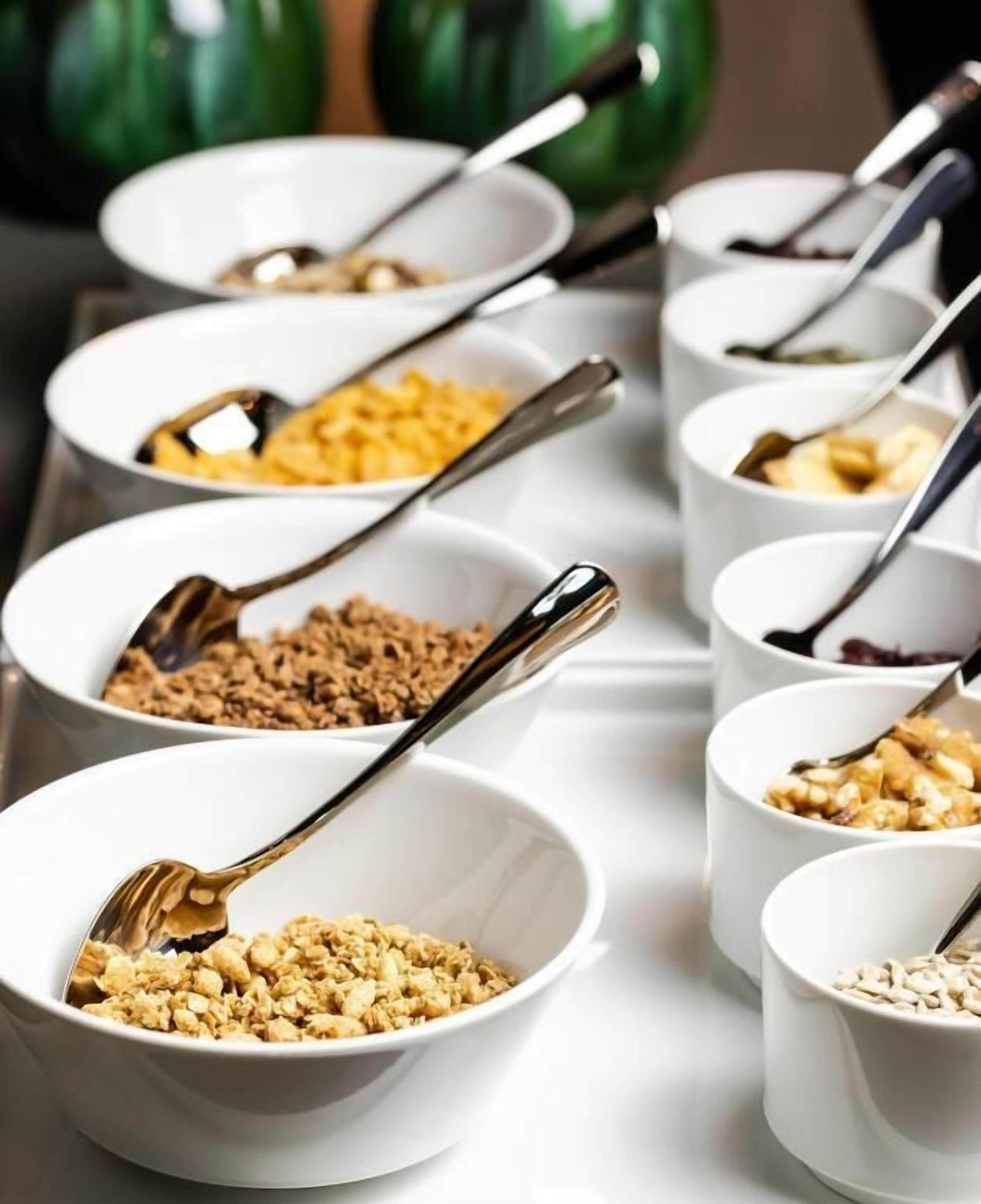 A series of white bowls with spoons, containing various food items.