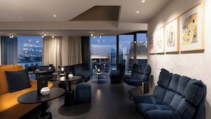 A modern lounge area with sofas, armchairs, and tables, featuring large windows with a city view. - KPM Hotel & Residences Berlin, a Member of Design Hotels (Berlin)