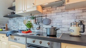 Une cuisine avec un mur de crédence en briques, des appareils en acier inoxydable et des meubles de couleur claire.