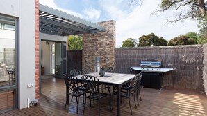 An outdoor patio with a table and chairs, a grill, and a stone wall. - Douglas Hide and Sea (COWES)