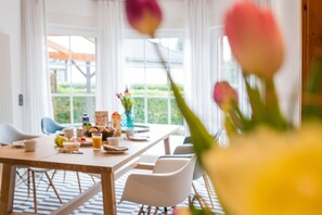 Un coin repas avec une table mise pour le petit-déjeuner, des chaises et une fenêtre donnant sur un paysage verdoyant.