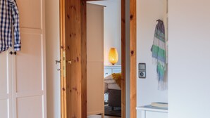 A hallway leading to a bedroom with a bed, a nightstand, and a lamp. - Triumph in der Heide (Buchholz (Aller))