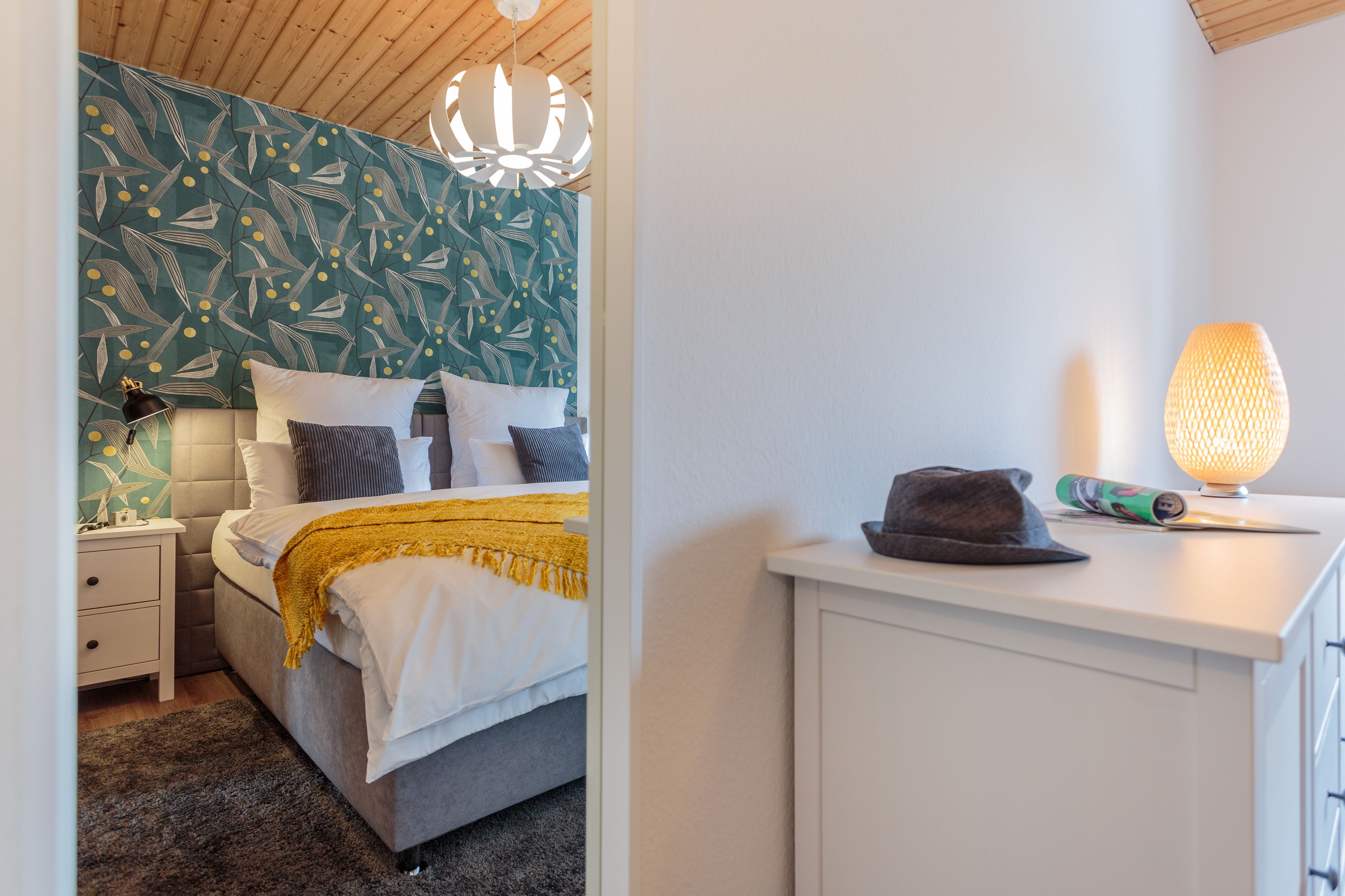 A bedroom with a bed, bedside lamp, and a nightstand.