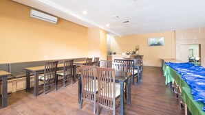 Un comedor con mesas y sillas de madera, una barra larga y una mesa cubierta con mantel azul.