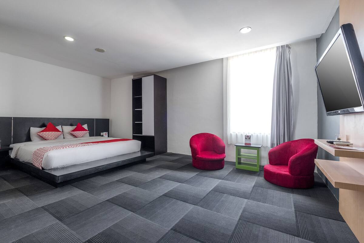 Ein modernes Hotelzimmer mit einem Bett, einem Schreibtisch, einem Fernseher und zwei Sesseln.