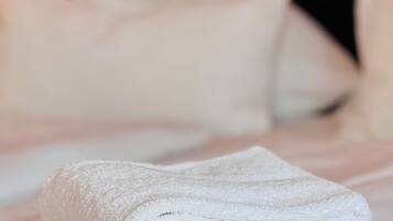 A neatly folded white towel on a bed with a black headboard and white pillows.