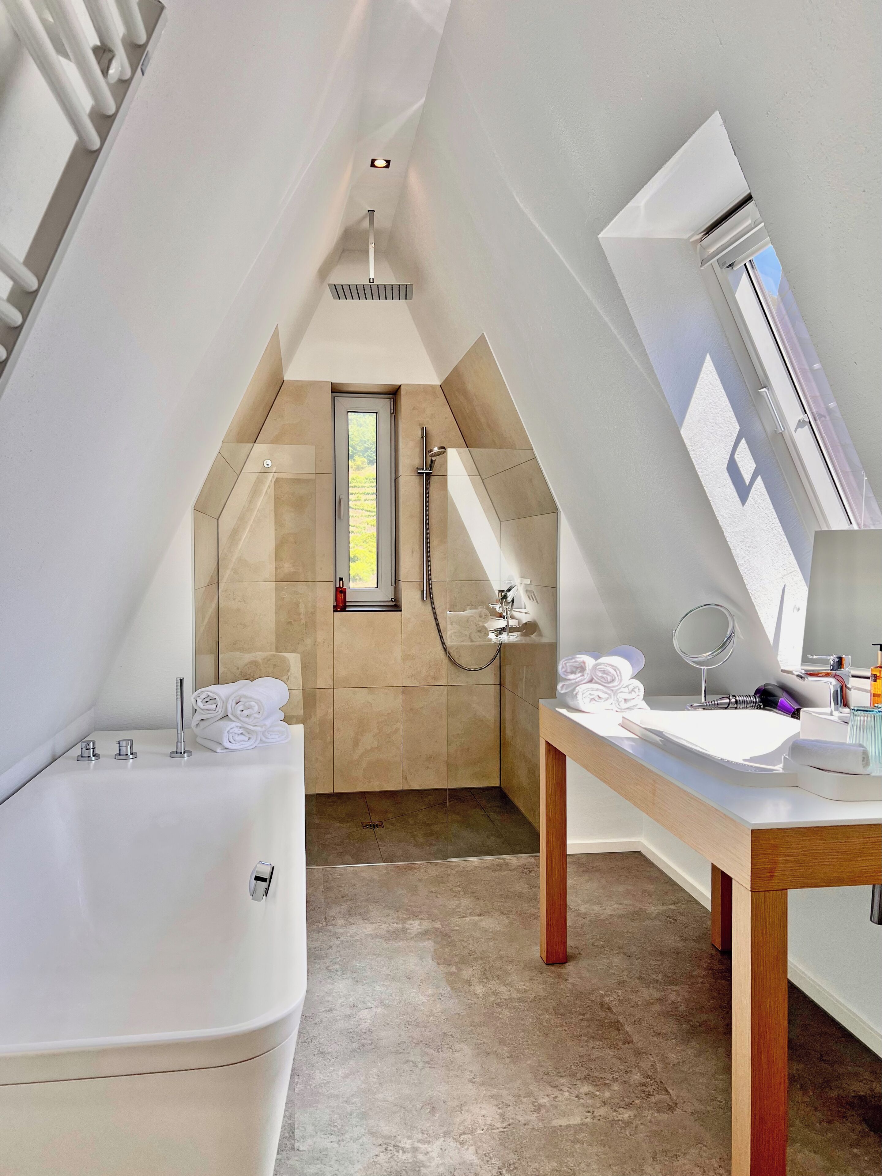 A modern bathroom with a bathtub, shower, vanity, and a skylight.