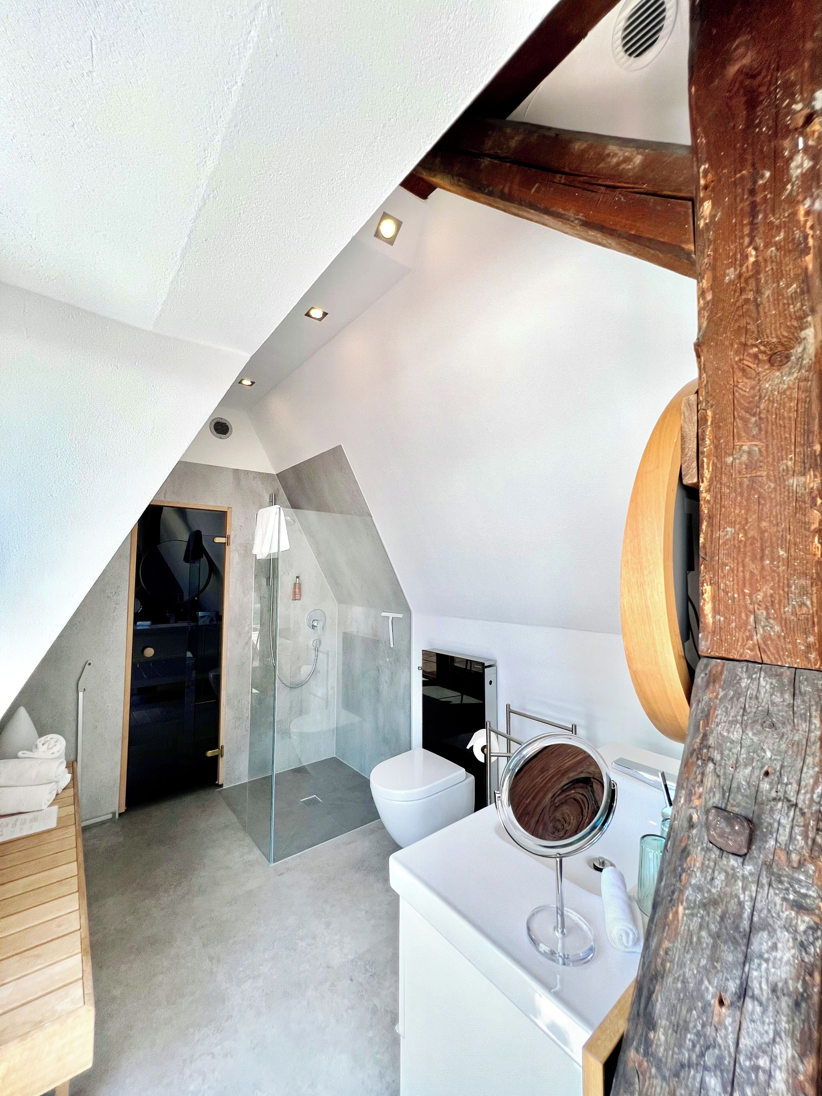 A modern bathroom with a glass shower enclosure, a white toilet, and a wooden vanity.
