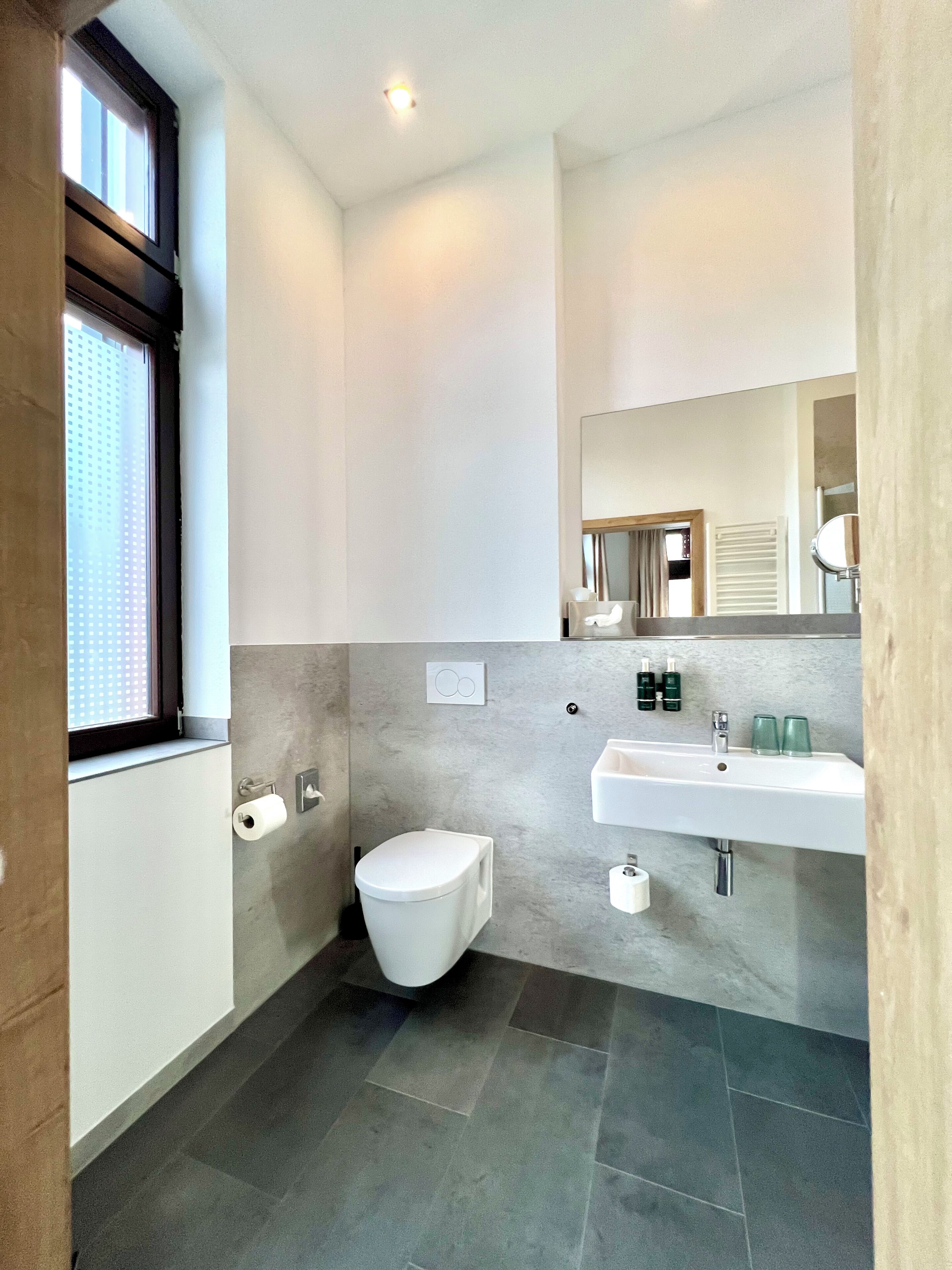 Een moderne badkamer met toilet, wastafel en spiegel.