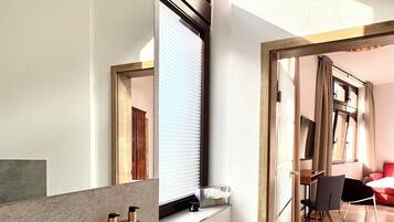 Un baño moderno con un espejo grande, un lavamanos y una ventana.