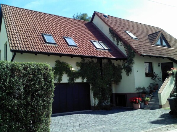 A two-story house with a tiled roof, a garage, and a paved driveway.