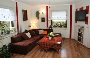 A living room with a brown sofa, a wooden coffee table, and a bookshelf.