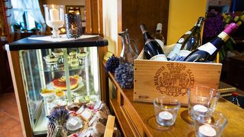 Una zona de bar con una vitrina de postres, una caja de madera con botellas de vino y un candelabro.