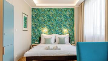 A hotel room with a bed, a blue chair, and a wall with a leafy pattern.