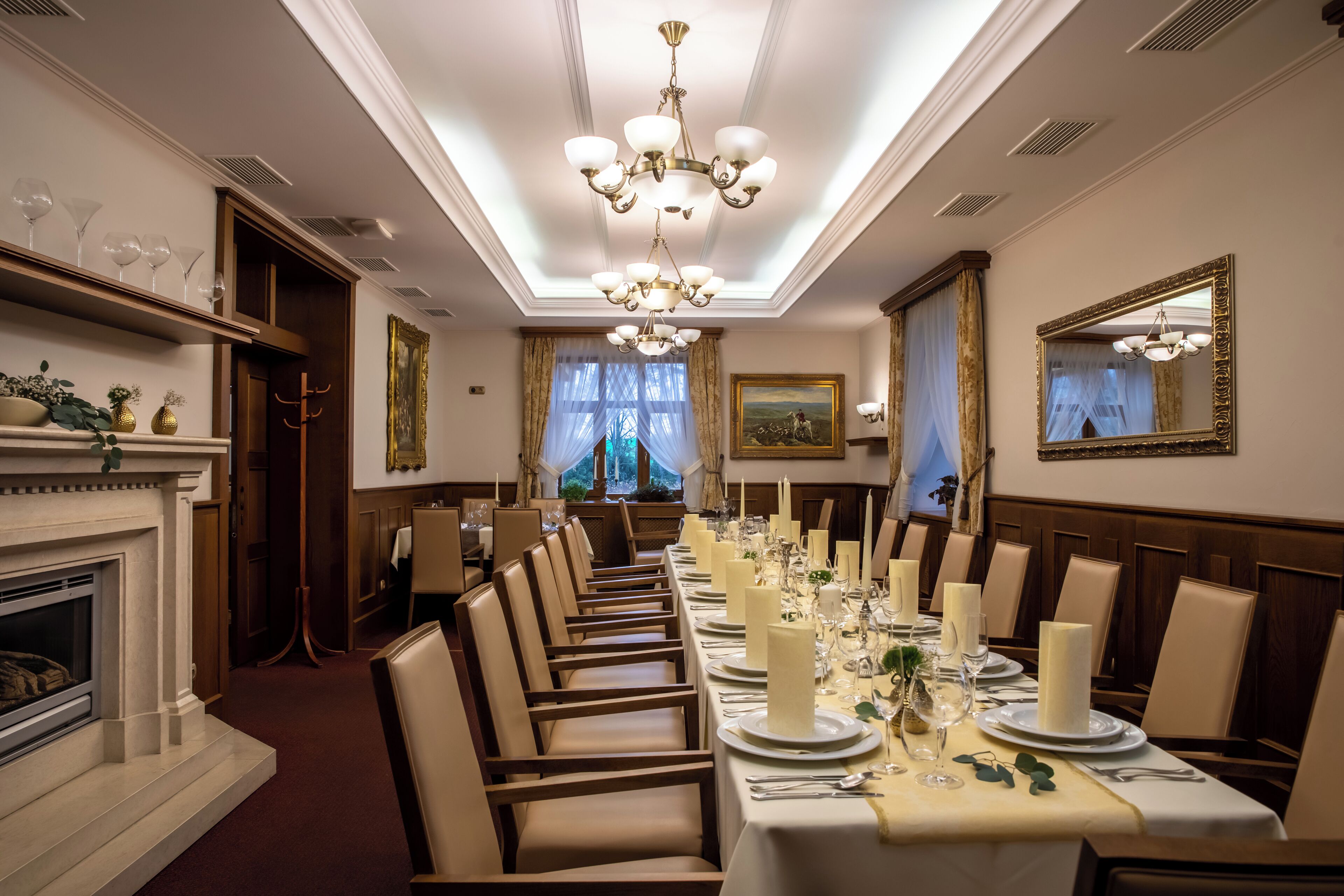 A long dining table set for a formal meal with candles, plates, and glasses.