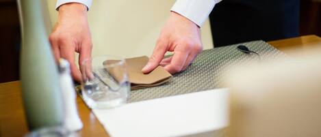 Una persona preparando una mesa con un mantel individual, una copa y una servilleta.