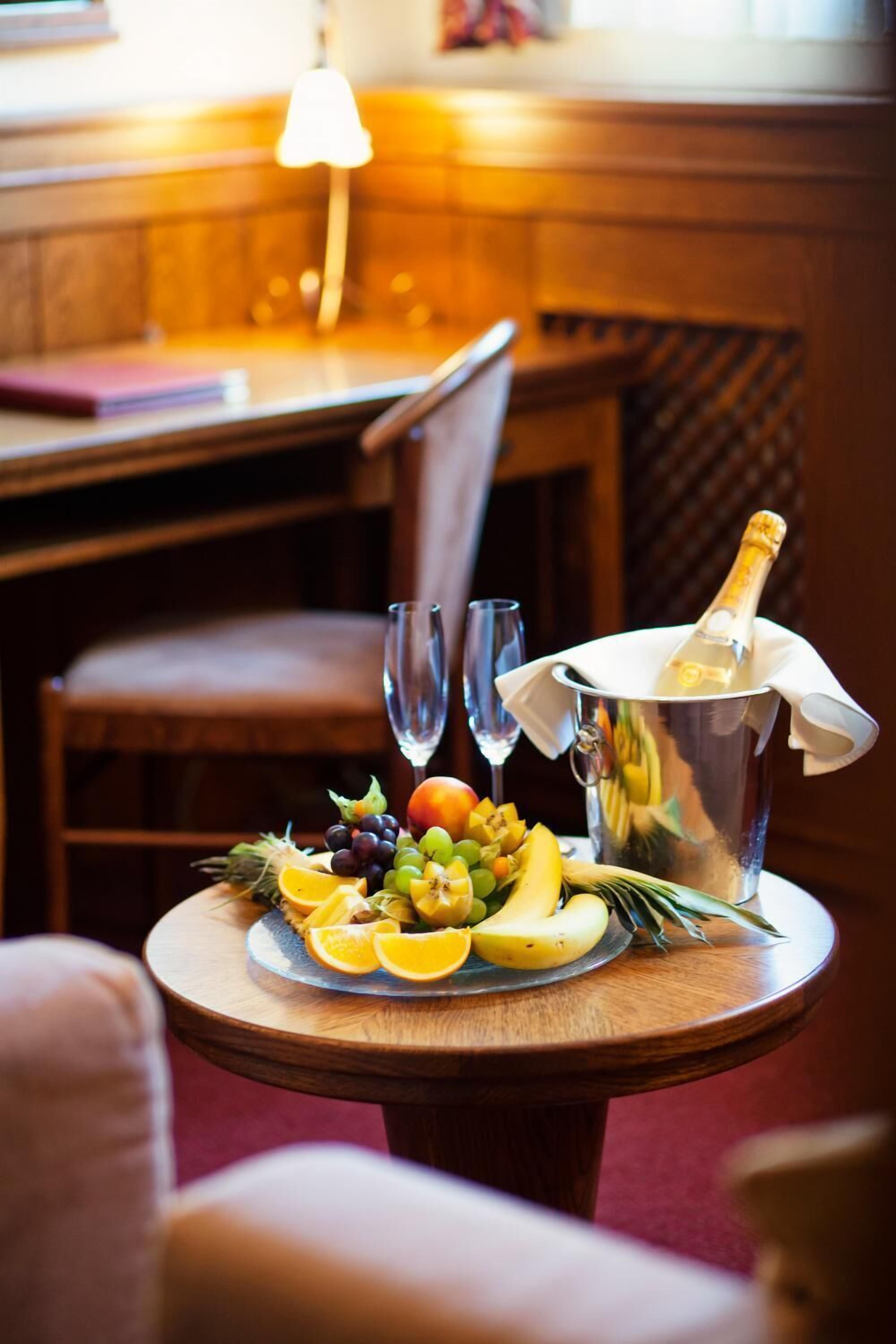 Een tafel met een fruitschaal, twee glazen en een champagnefles.