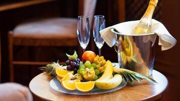 Een tafel met een fruitschaal, twee glazen en een champagnefles.