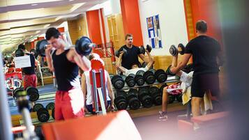 Un gimnasio con equipo de levantamiento de pesas y un espejo que refleja el espacio.