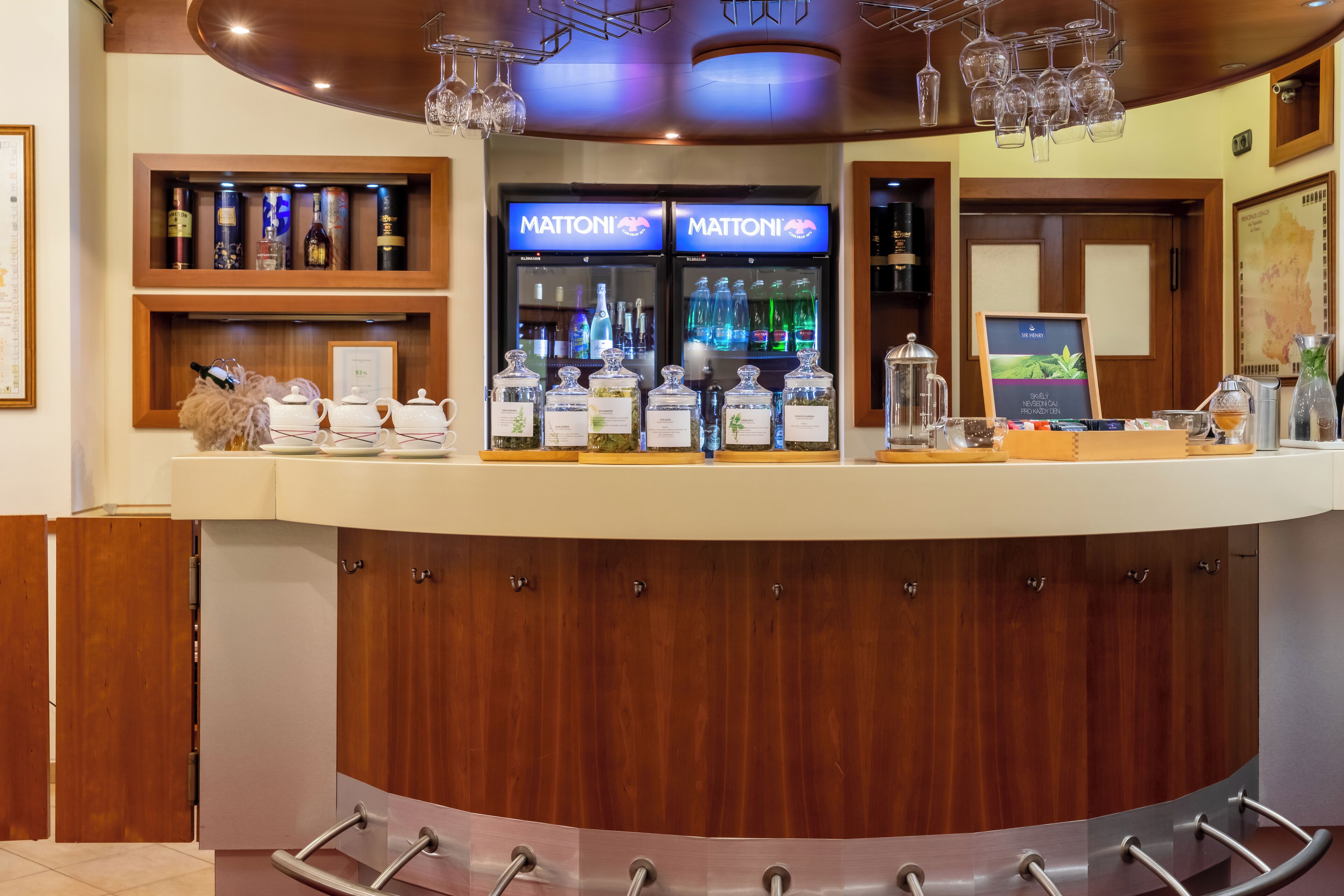 A bar area with a wooden counter, wine bottles, and a minibar.