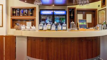 A bar area with a wooden counter, wine bottles, and a minibar.