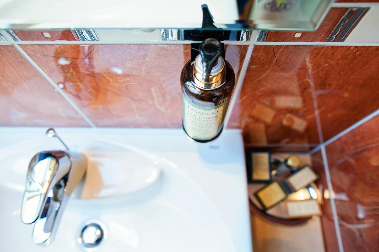 Ein Badezimmer mit Waschbecken, Spiegel und einer Shampooflasche.