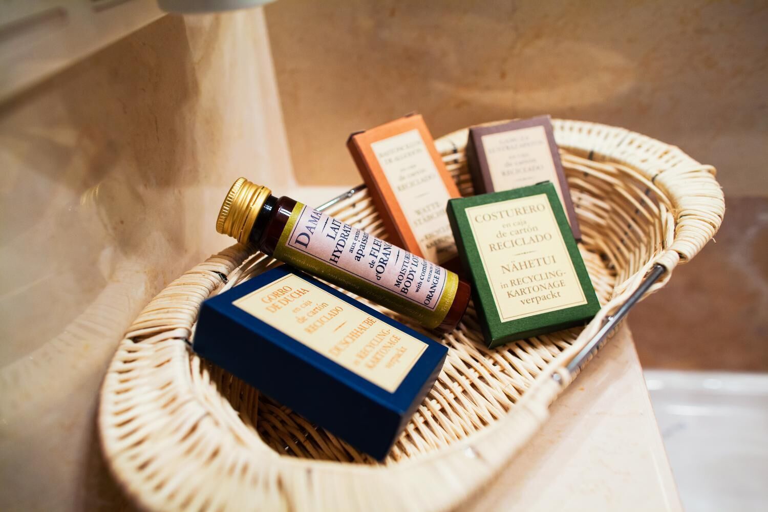 Una cesta de mimbre con varios productos envasados, incluyendo una botella y cajas con etiquetas.