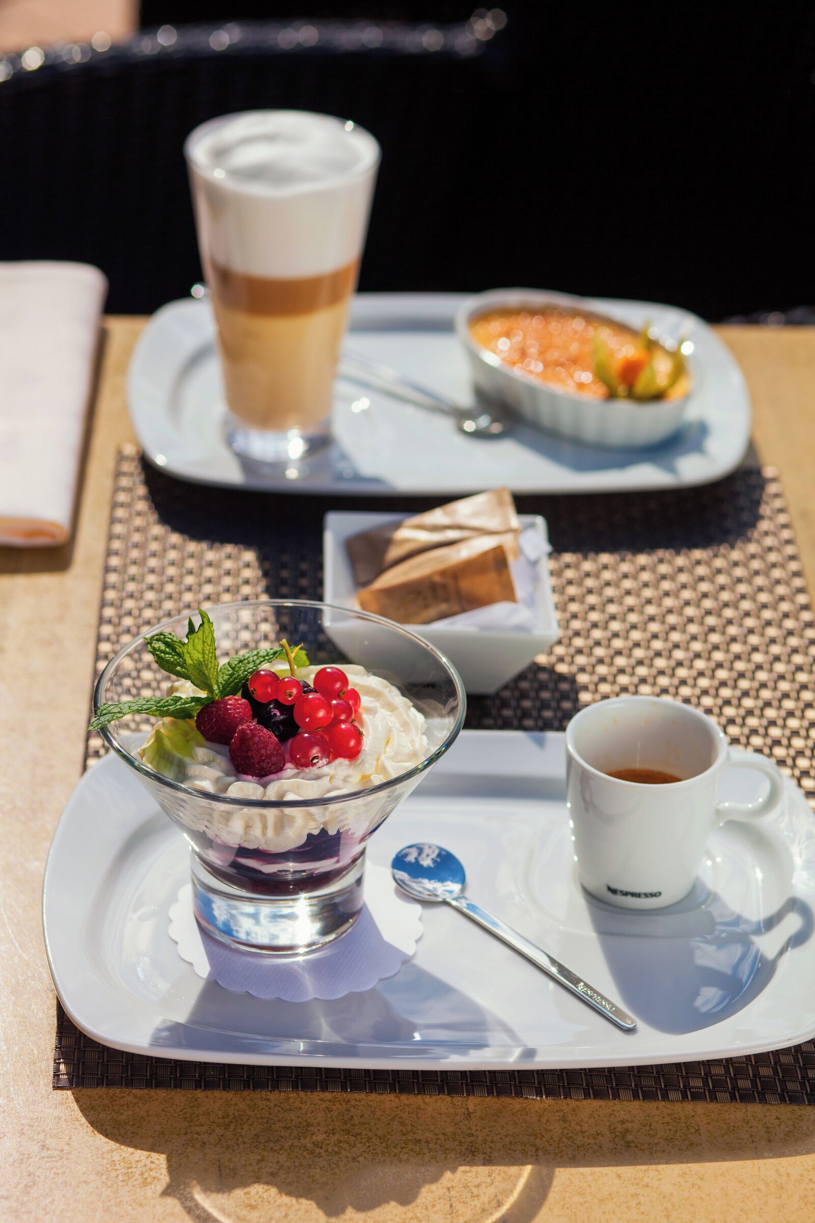 Una bandeja de postres con una taza de café, un tazón de bayas y un recipiente pequeño de chocolate.