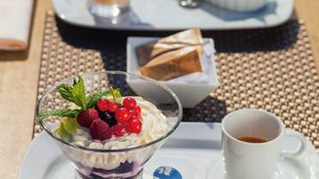 Una bandeja de postres con una taza de café, un tazón de bayas y un recipiente pequeño de chocolate.