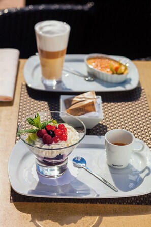 Una bandeja de postres con una taza de café, un tazón de bayas y un recipiente pequeño de chocolate.