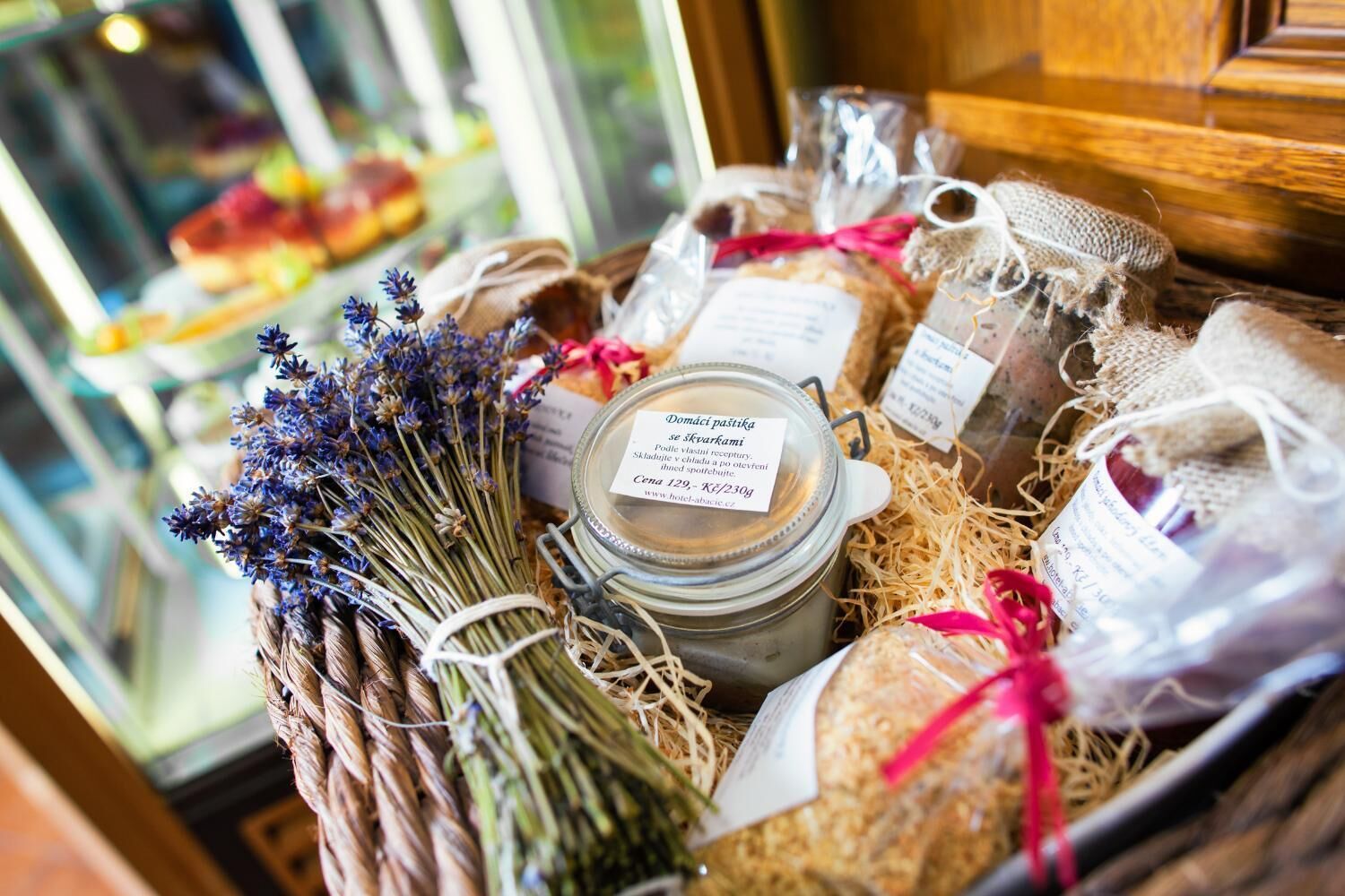 Esposizione di diversi prodotti alimentari, tra cui vasetti di conserve, pane e un cesto di lavanda.