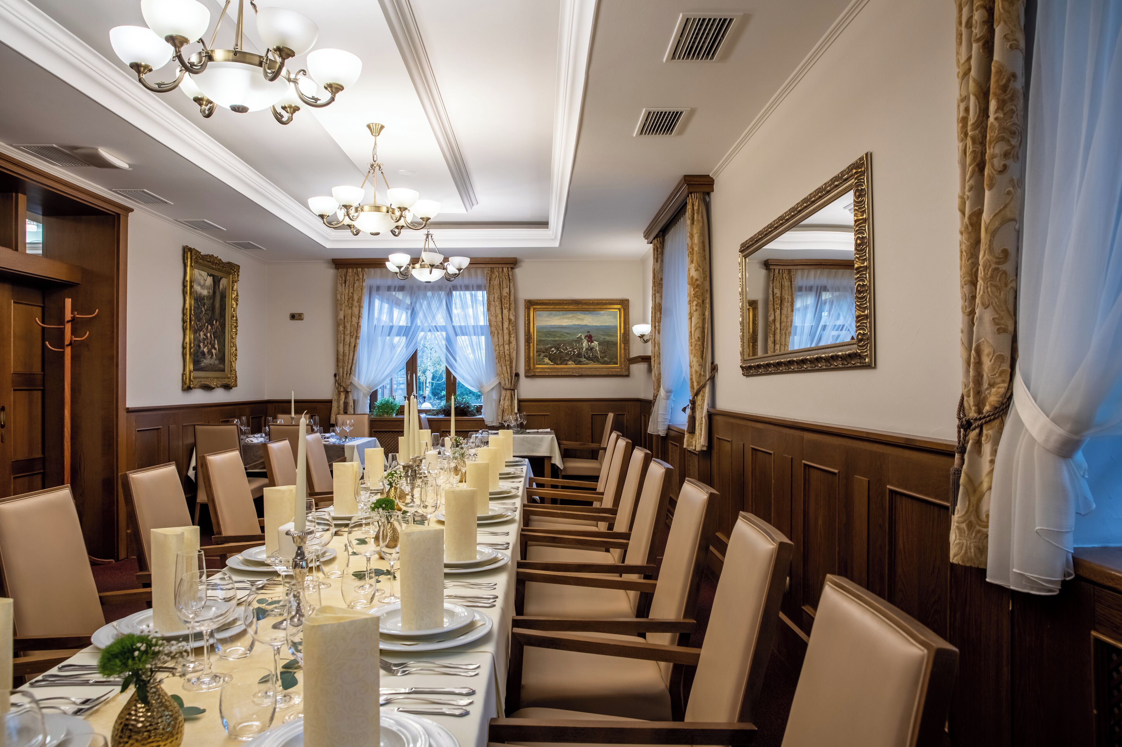 Un comedor formal con una larga mesa dispuesta para una comida, candelabros elegantes y decoración clásica.