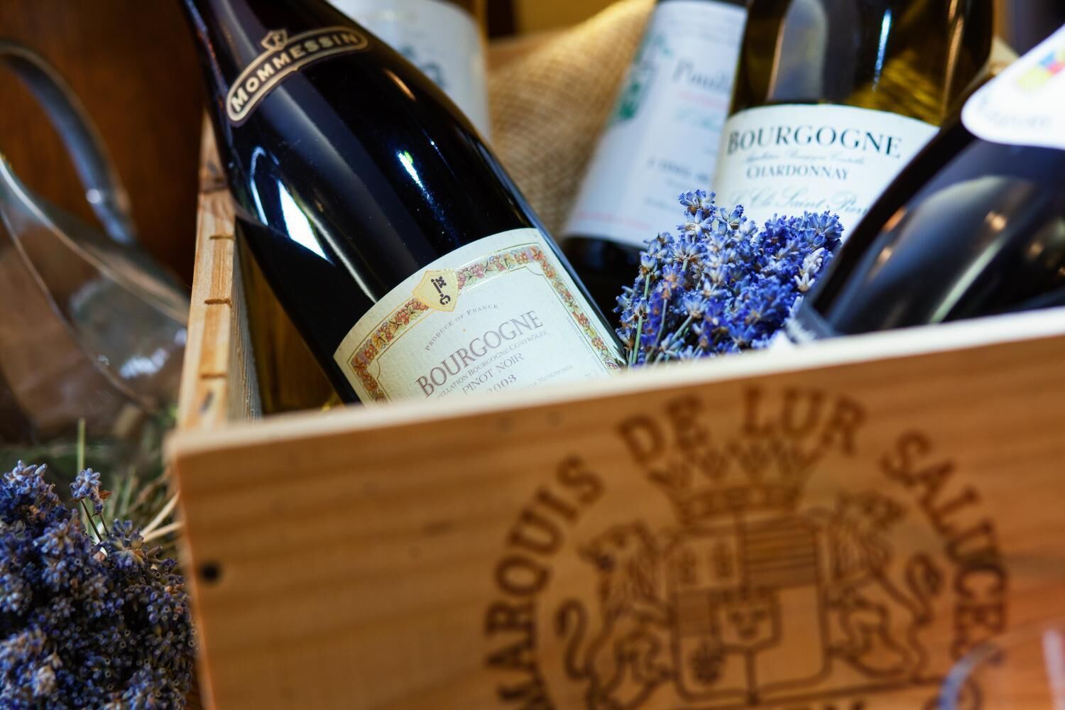 Una caja de madera llena de botellas de vino, incluyendo un Bourgogne Pinot Noir.