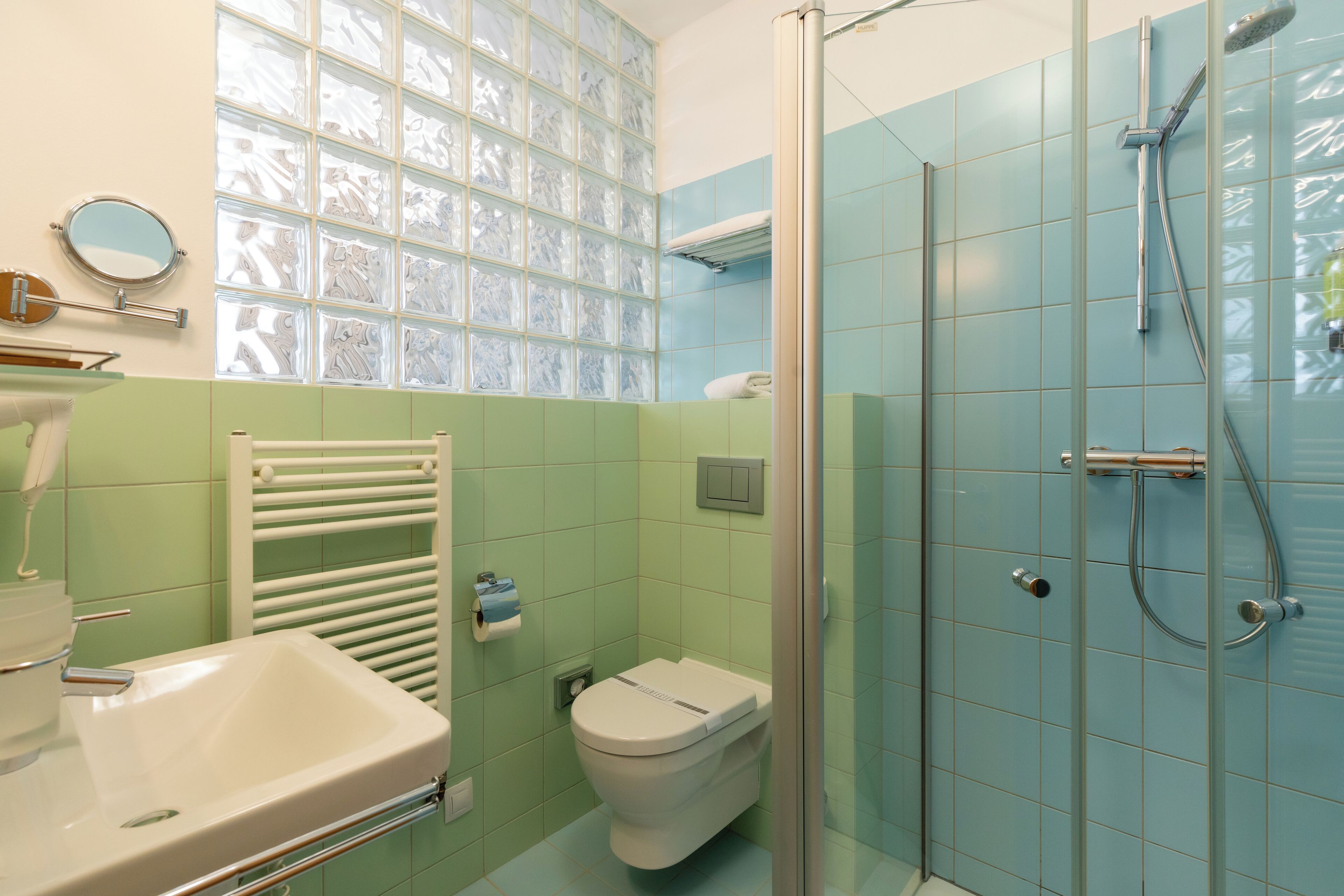Een badkamer met een douchecabine van glas, een wit wastafelmeubel en een toilet.