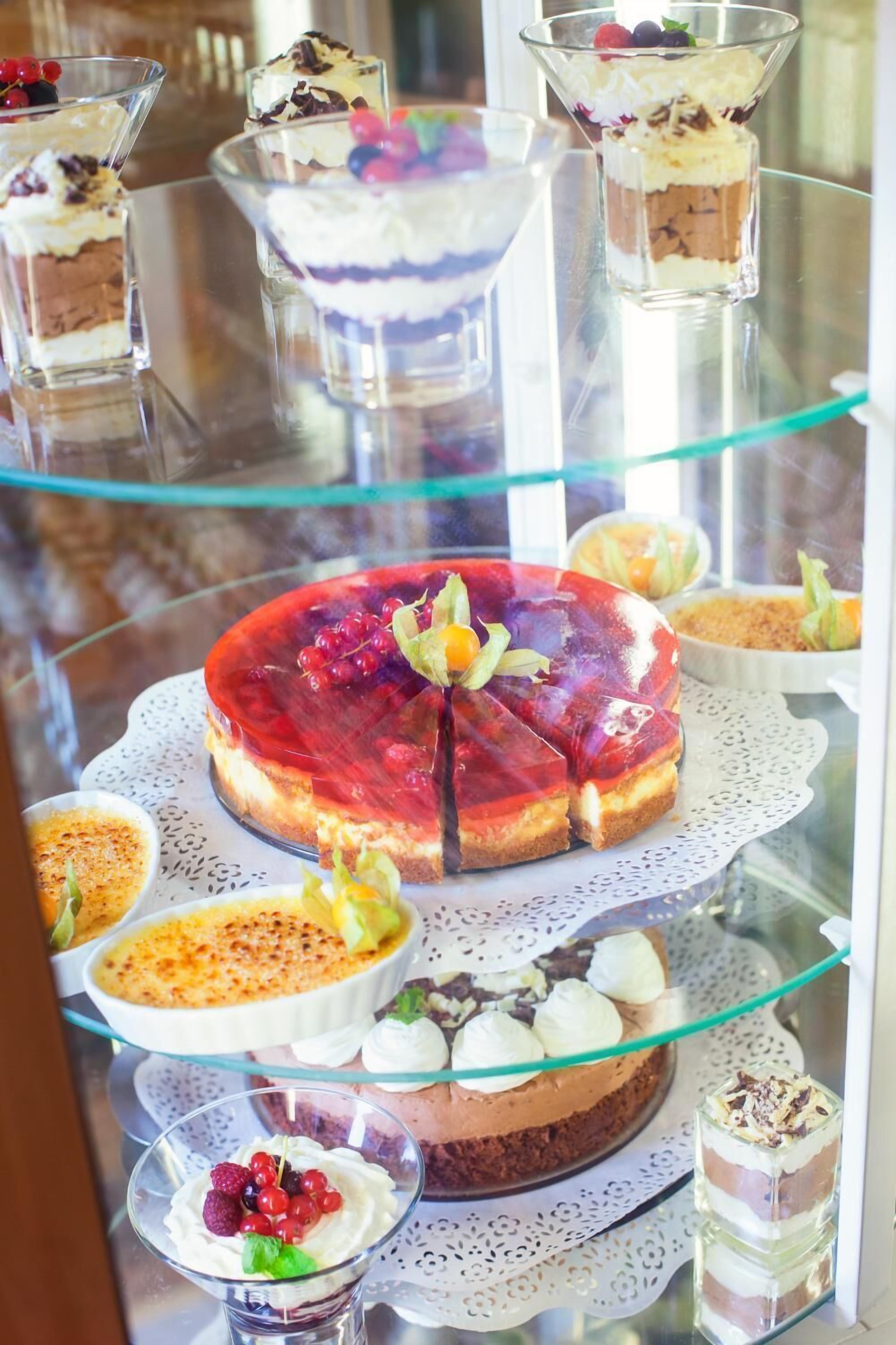 Un présentoir à desserts avec divers gâteaux et pâtisseries disposés sur des étagères en verre.