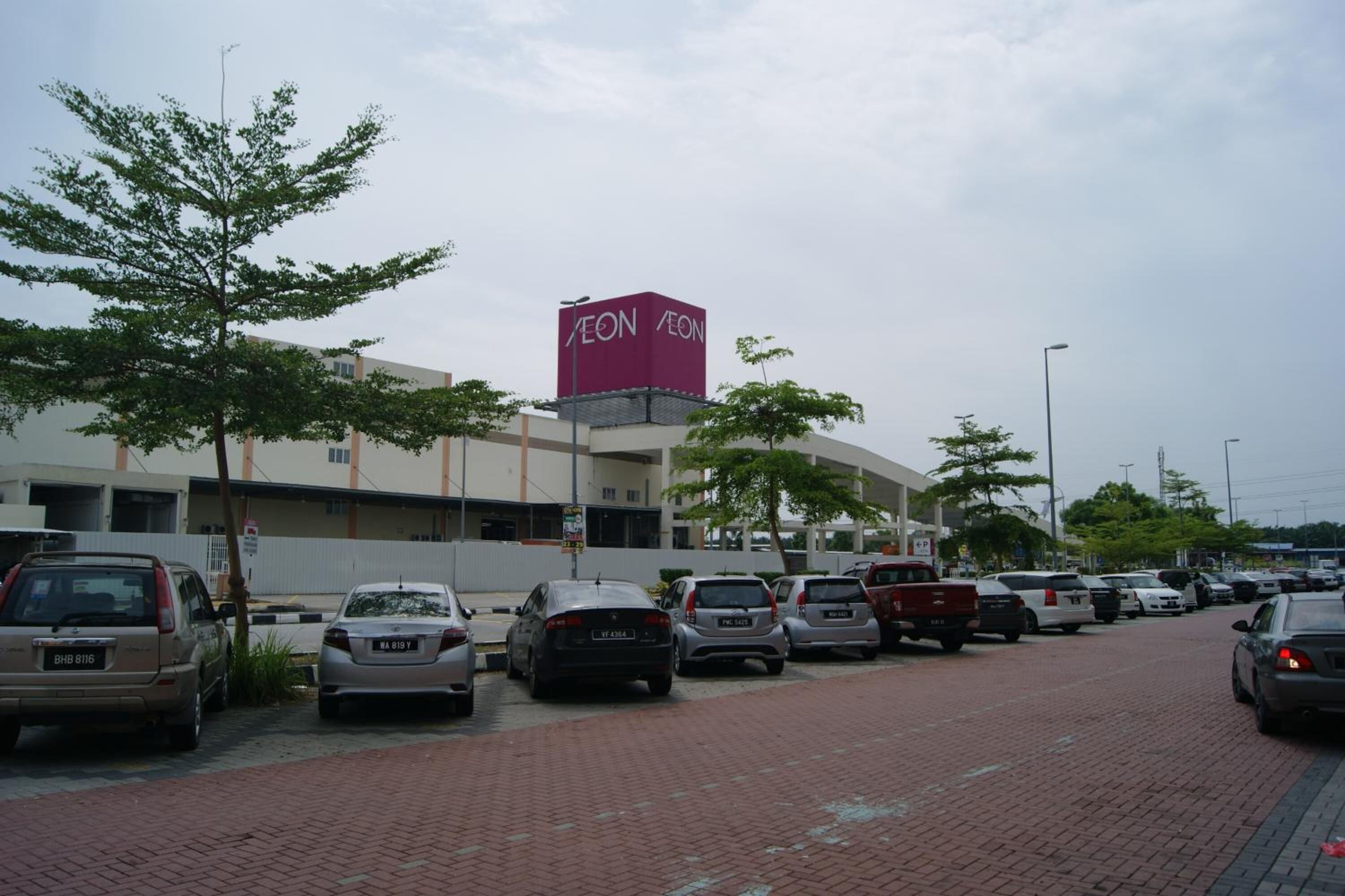 A parking lot with several cars and a building with a prominent 'AEON' sign.