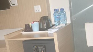 A compact kitchenette with a coffee maker, water bottles, and a small refrigerator. - Double Happiness Hotel (Seri Manjung)